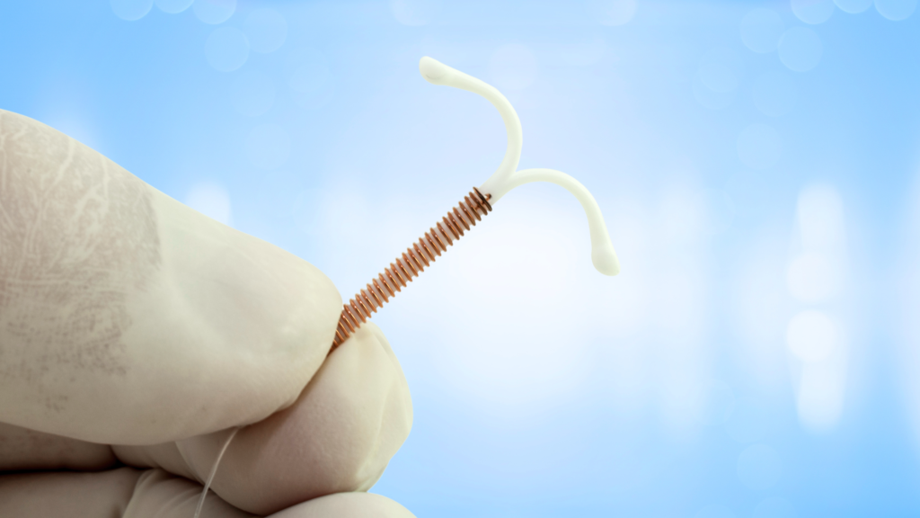 gloved hand holding an intrauterine device IUD