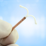 gloved hand holding an intrauterine device IUD