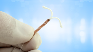 gloved hand holding an intrauterine device IUD