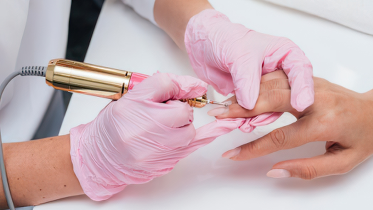 Woman's hands getting a russian manicure with a mechanical electrical drill file to trim cuticles