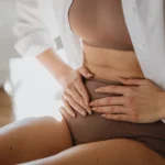 woman holding abdomen with chronic pelvic pain from pelvic congestion syndrome