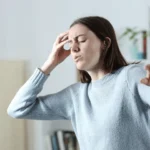 woman holding her head dizzy trying not to lose balance as she stands up postural orthostatic tachycardia syndrome pots