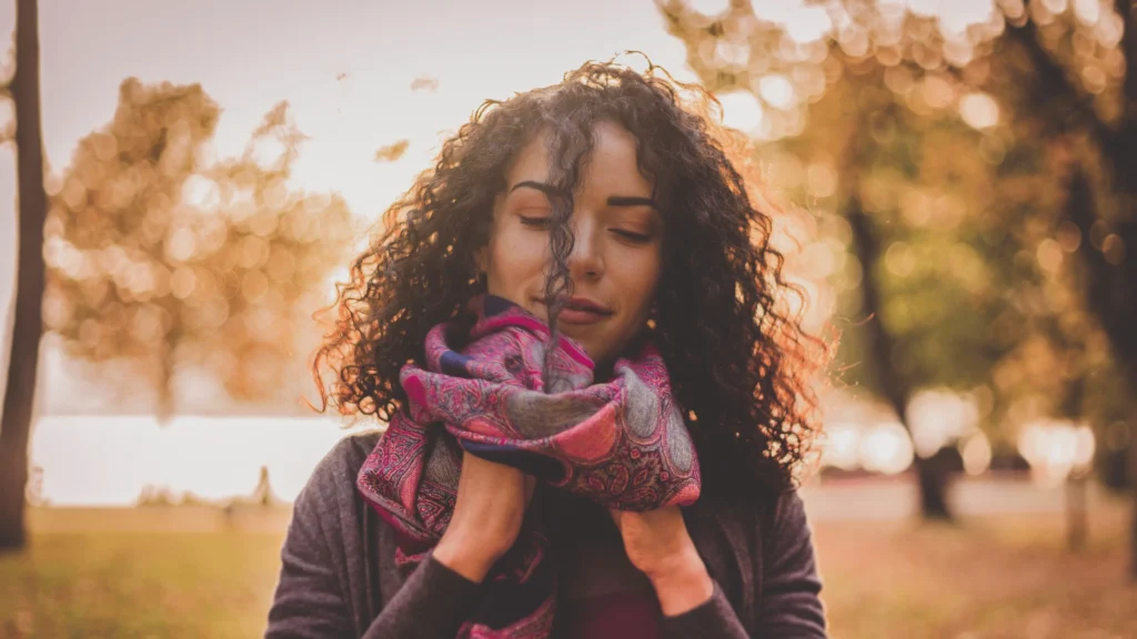 woman with curly hair in cold autumn weather with scarf